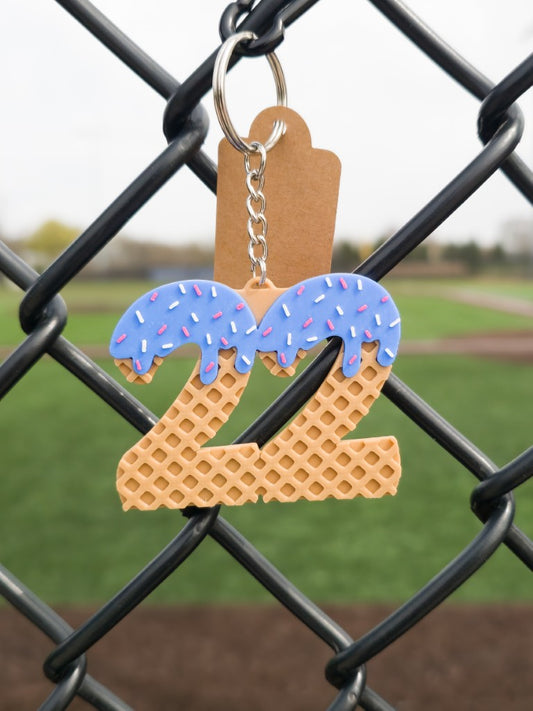 Keychain with a waffle number '22' and blue icing on a chain link fence.