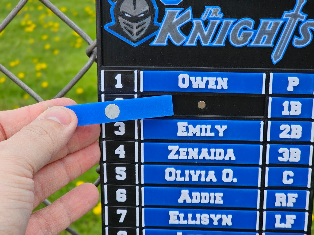 Hand holding a blue name tag in front of a sports team roster board with names and positions.